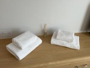 two white towels sitting on top of a wooden dresser at Delightful self-contained Annexe close to airport in Norwich +20 photos