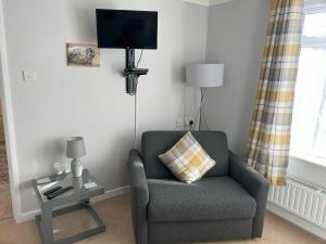 a living room with a chair and a tv at Delightful self-contained Annexe close to airport in Norwich
