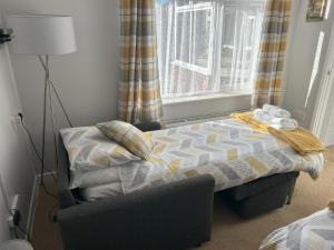 a bedroom with a bed and a chair and a window at Delightful self-contained Annexe close to airport in Norwich
