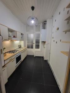 a kitchen with white cabinets and a black floor at appartement style haussmannien in Brussels