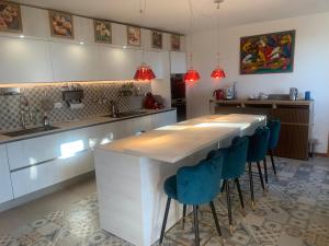 a kitchen with a long counter with blue bar stools at VILLA TARA in Quercianella