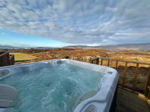 a jacuzzi tub on a deck with a view at Duirinish Pods with Private Hot Tubs and Duirinish Bothy with No Hot Tub in Plockton