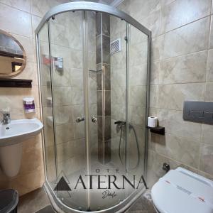 a shower in a bathroom with a toilet and a sink at ATERNA HOTEL in Dikili