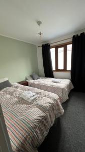 two beds in a room with a window at Anoka House in Punta Arenas