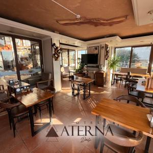 un restaurante con mesas y sillas de madera y ventanas en ATERNA HOTEL, en Dikili