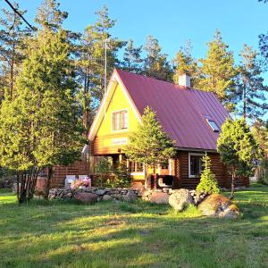 ein Holzhaus mit rotem Dach auf einem Feld in der Unterkunft Lootuse Spa in Nõmmemaa