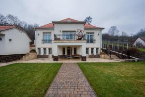 a large white house with a lawn in front of it at Völgy Villa in Zebegény