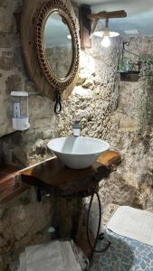 uma casa de banho com um lavatório e um espelho numa parede de pedra em Dimora Forgione B&B - Pietrelcina em Pietrelcina
