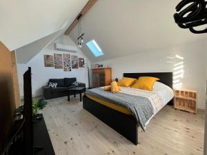 sypialnia z łóżkiem z żółtymi poduszkami i kanapą w obiekcie Le Clos des Maraîchers w mieście Village-Neuf