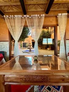 uma sala de estar com uma mesa de vidro com cortinas em Riad Tamdakhte em Aït-Ben-Haddou