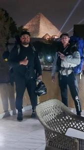 two men are standing next to a bench at night at Ramses Guest House in Cairo