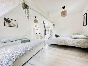 2 letti in una camera da letto con pareti bianche e pavimenti in legno di Maison Médiévale a Laon