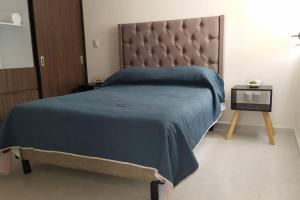 a bedroom with a bed with a blue blanket and a table at Dpto en Altozano 34 in Morelia