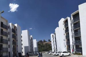 莫雷利亞的住宿－Dpto en Altozano 34，停车场内一排白色的建筑,有汽车停放