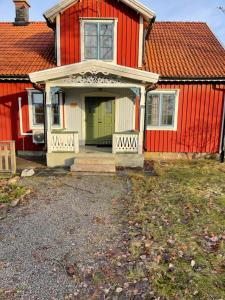a red house with a green door in front of it at Vacker villa i Fröseke in Fröseke