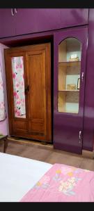 a bedroom with a purple wall and a wooden cabinet at Feel the Bong vibes in a villa nearest to airport. in Kolkata
