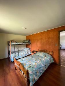 1 dormitorio con 2 camas y pared de madera en Cabaña Curacautín “Refugio Cautin”, en Curacautín
