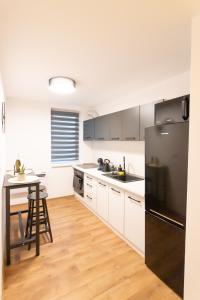 uma cozinha com armários brancos e um frigorífico preto em MAT Apart em Topliţa