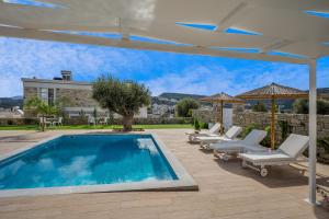 a swimming pool with lounge chairs and an umbrella at Aphrodite's Luxury Pearls 2 in Pitsidia