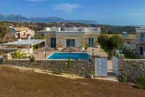 a house with a swimming pool and a stone wall at Aphrodite's Luxury Pearls 2 in Pitsidia