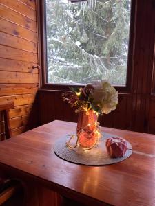 un jarrón con flores sobre una mesa con una ventana en ChillHouse, en Loučná nad Desnou