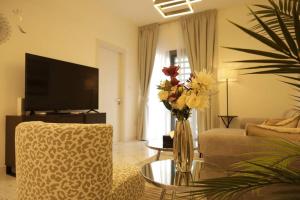 a living room with a vase of flowers on a table at Amber Glow 2BR Apartment Al Raha in Abu Dhabi