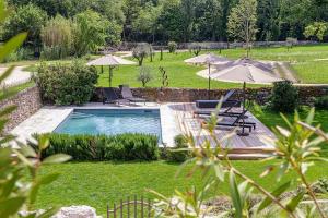 una piscina en un patio con sombrillas en Le Moulin Dumas, en Grignan