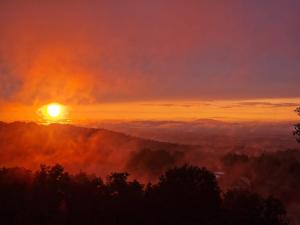 a sunset on a mountain with the sun in the background at Fugger Alm in Weichselbaum