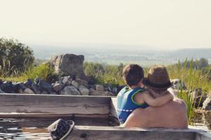 Ein Mann und ein Junge sitzen auf einem hölzernen Felsvorsprung in der Unterkunft Fugger Alm in Weichselbaum