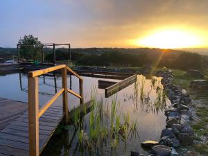a sunset over a pond with a wooden boardwalk at Fugger Alm in Weichselbaum