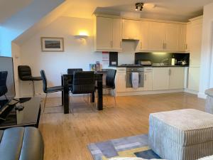 a living room with a table and a kitchen at Harbour Penthouse Whitby in Whitby