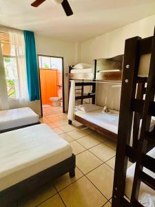 a room with two bunk beds and a bathroom at Casa de Lis Hotel & Tourist Info Centre in Turrialba