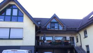 a house with a balcony with tables and chairs at Ferienwohnung Schädel in Reichshof 