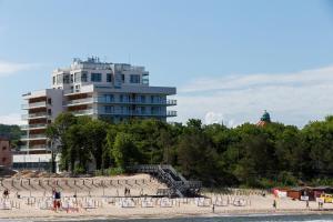 a group of people on a beach with a building at Aquamarina Prima Holiday Studios by the BEACH by Renters in Międzyzdroje