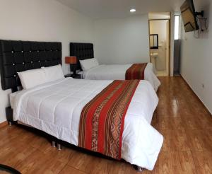 a bedroom with two beds and a television in it at Cusco de mis Sueños Hostal - II in Cusco