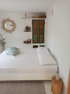 Gîte mziraa في Hammamet Sud: غرفة نوم بسرير ابيض ومرآة