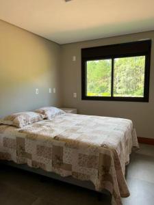 um quarto com uma cama grande e uma janela em Chácara 7 - A sua casa em Rancho Queimado em Rancho Queimado