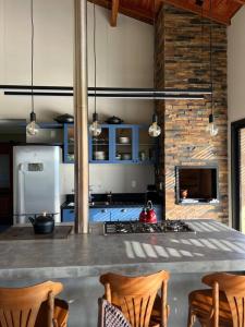 uma cozinha com um balcão com cadeiras e um fogão em Chácara 7 - A sua casa em Rancho Queimado em Rancho Queimado
