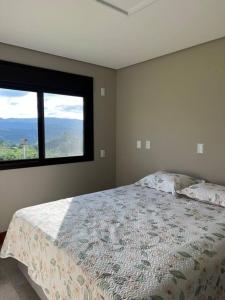 um quarto com uma cama e uma grande janela em Chácara 7 - A sua casa em Rancho Queimado em Rancho Queimado