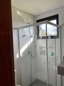 uma casa de banho com um chuveiro e uma porta de vidro em Chácara 7 - A sua casa em Rancho Queimado em Rancho Queimado