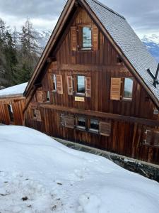 un grande edificio in legno con neve sul terreno di Chalet Les Portes a Riddes