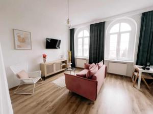 a living room with a couch and two windows at Apartament Pastelowy Kwidzyn in Kwidzyn
