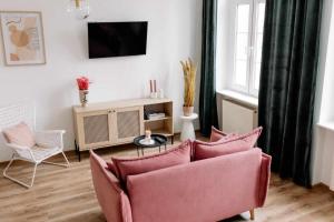 a living room with a pink couch and a tv at Apartament Pastelowy Kwidzyn in Kwidzyn