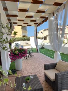 patio ze stołem, krzesłami i kwiatami w obiekcie Le residenze del mare Affittacamere w mieście La Caletta