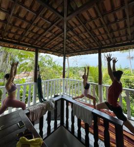 three women on a porch with their arms in the air at Hostel Zen - Casa na Floresta in Itacaré