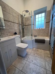 a bathroom with a toilet and a tub and a sink at Apartment in the Countryside with Hot Tub in Trowbridge