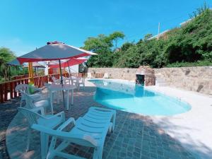 einen Pool mit Stühlen, einem Tisch und einem Sonnenschirm in der Unterkunft Punta Cocos Beach Casitas in Zorritos
