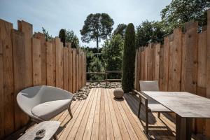 une terrasse en bois avec des chaises, une table et une clôture dans l'établissement Hôtel Le Parc - La Table de Franck Putelat, à Carcassonne
