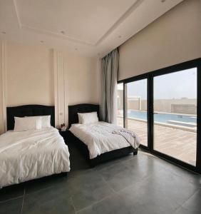 two beds in a bedroom with a view of a pool at Al Saleh Chalet in Al Ashkharah