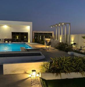 a house with a swimming pool at night at Al Saleh Chalet in Al Ashkharah